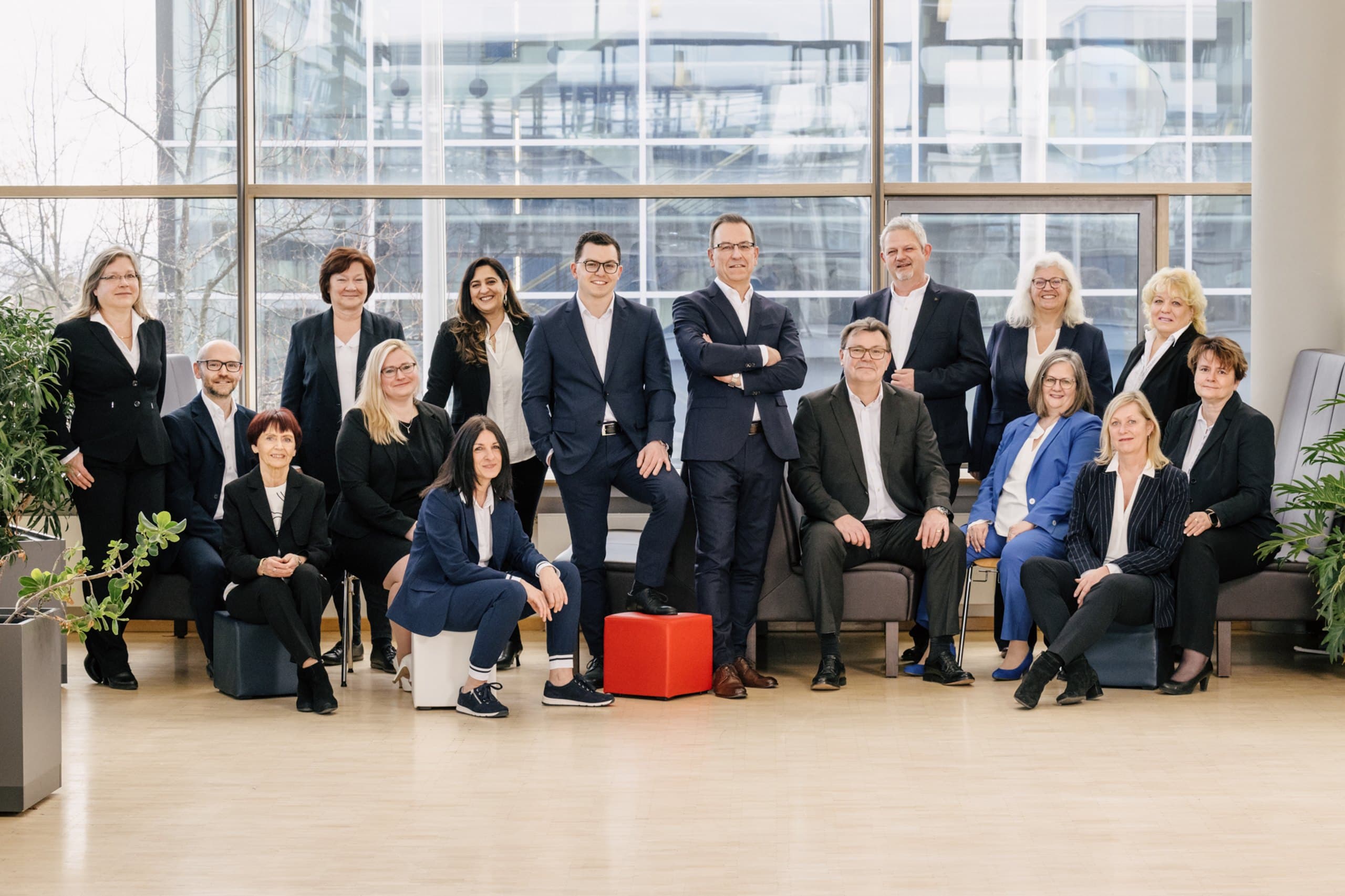 Das Team der Treuhand Stuttgart GmbH in Businesskleidung als Gruppenfoto im hellen Bürofoyer