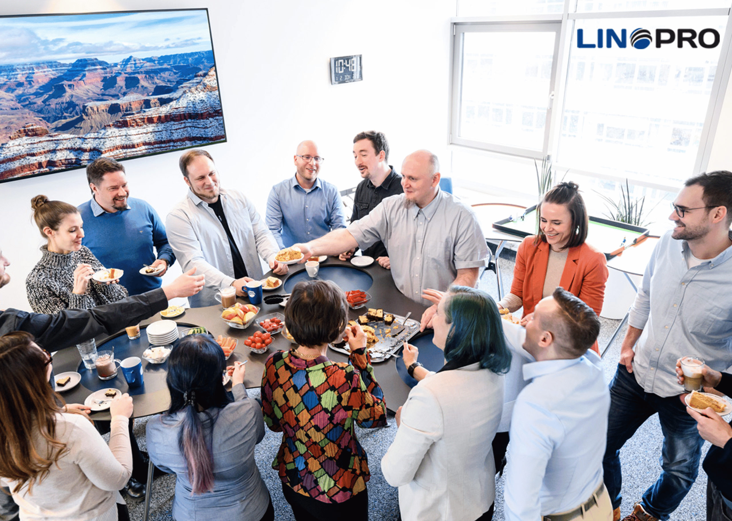 Das LinoPro-Team steht bei einer Kuchen- und Kaffeerunde um einen Tisch im Büro
